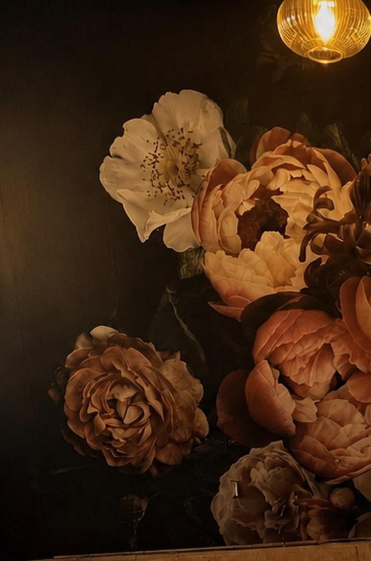 The floral feature wall at The Bottle Poet under a warm pendant light